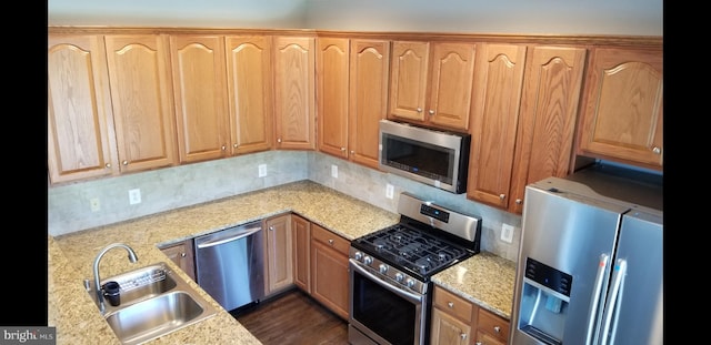 kitchen featuring decorative backsplash, sink, light stone counters, and stainless steel appliances