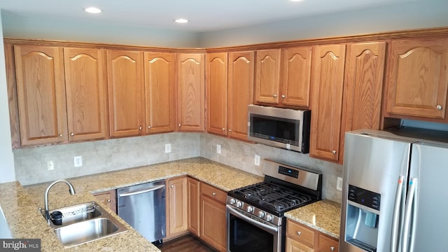 kitchen with light stone countertops, stainless steel appliances, tasteful backsplash, and sink