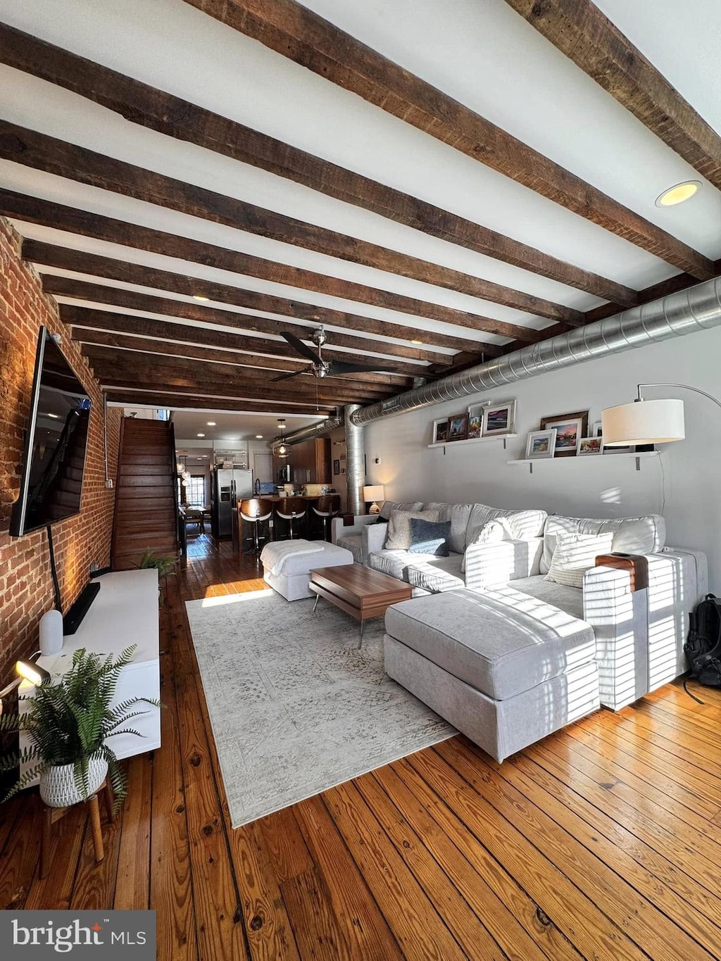 living room with ceiling fan, brick wall, and hardwood / wood-style floors