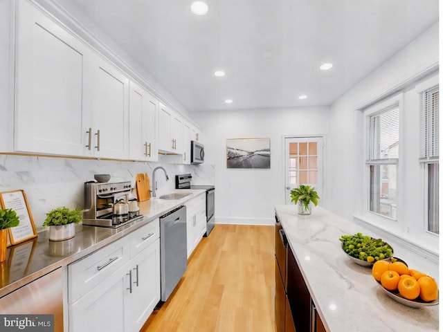 kitchen featuring light stone counters, sink, white cabinetry, and stainless steel appliances