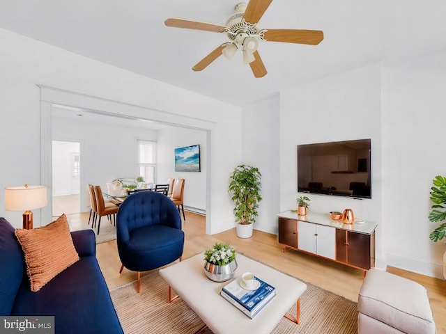 living room with ceiling fan, a baseboard heating unit, and light hardwood / wood-style floors