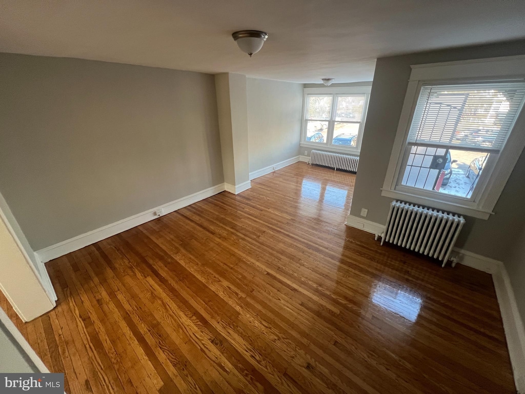 spare room featuring radiator and hardwood / wood-style floors