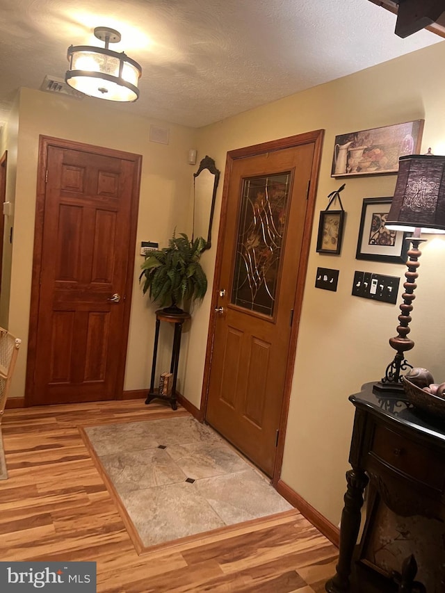 foyer entrance featuring a textured ceiling and light hardwood / wood-style flooring