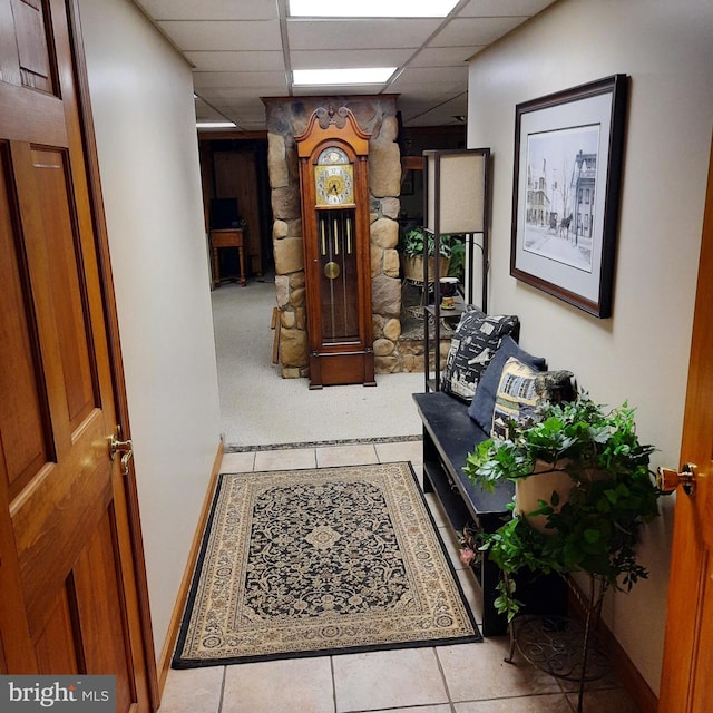 corridor with a drop ceiling and light tile patterned floors