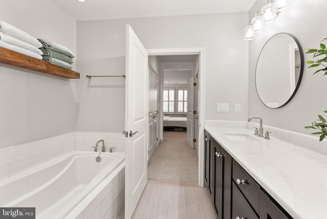 bathroom with tiled tub and vanity