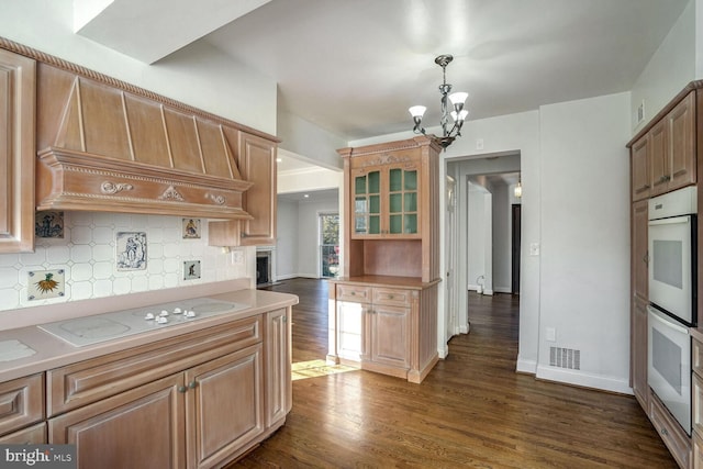 kitchen featuring ventilation hood, dark hardwood / wood-style flooring, decorative backsplash, hanging light fixtures, and white appliances