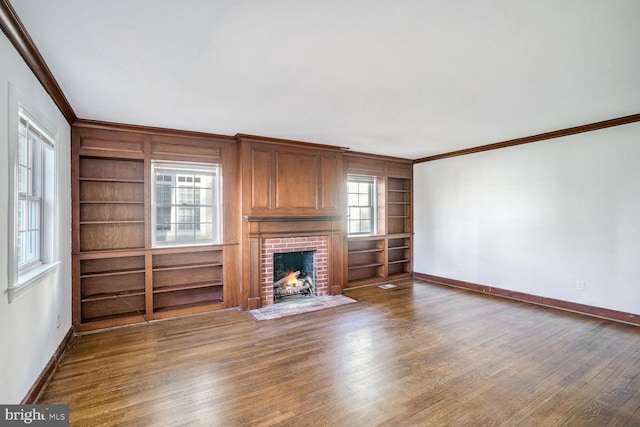 unfurnished living room with ornamental molding, a brick fireplace, wood-type flooring, and built in features