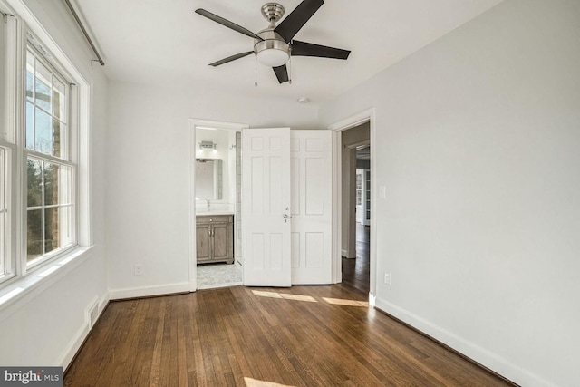 unfurnished bedroom with ensuite bathroom, dark hardwood / wood-style floors, and ceiling fan