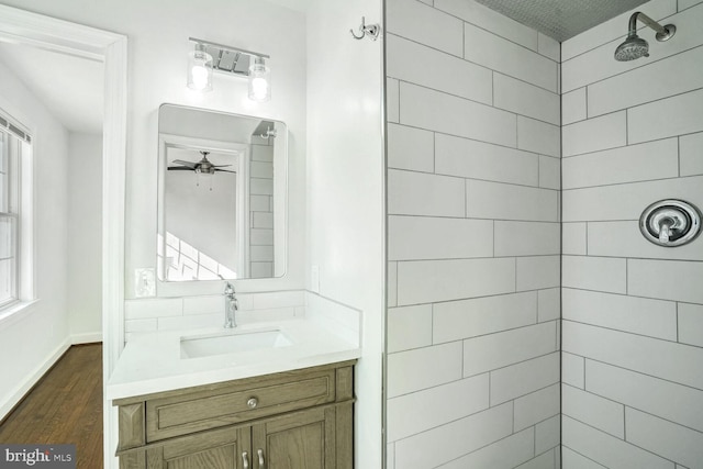 bathroom featuring a tile shower, hardwood / wood-style floors, vanity, and a healthy amount of sunlight