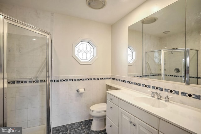 bathroom featuring a shower with door, tile walls, tile patterned flooring, vanity, and toilet