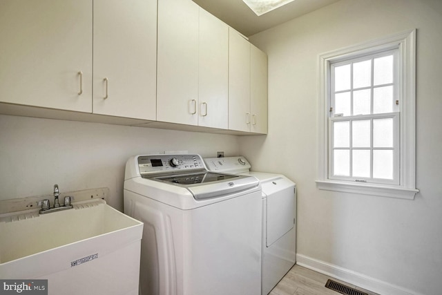 clothes washing area featuring cabinets, washer and clothes dryer, sink, and light hardwood / wood-style flooring