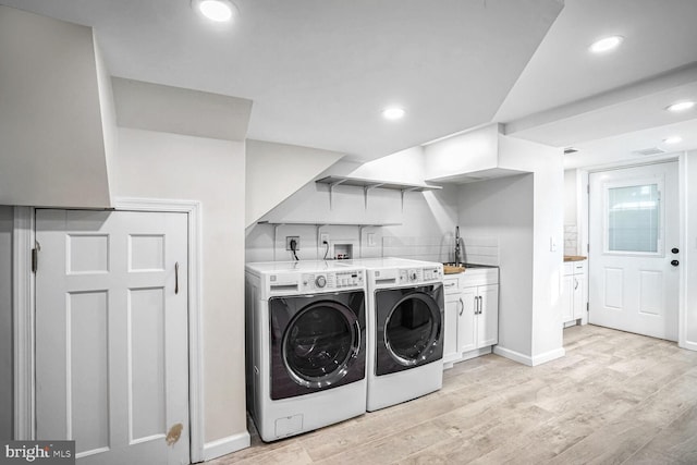 laundry room featuring cabinets, separate washer and dryer, and light hardwood / wood-style floors