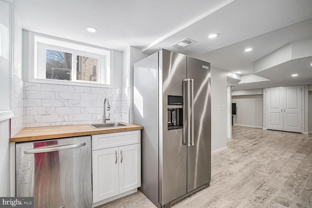 kitchen featuring sink, white cabinets, wooden counters, stainless steel appliances, and light wood-type flooring