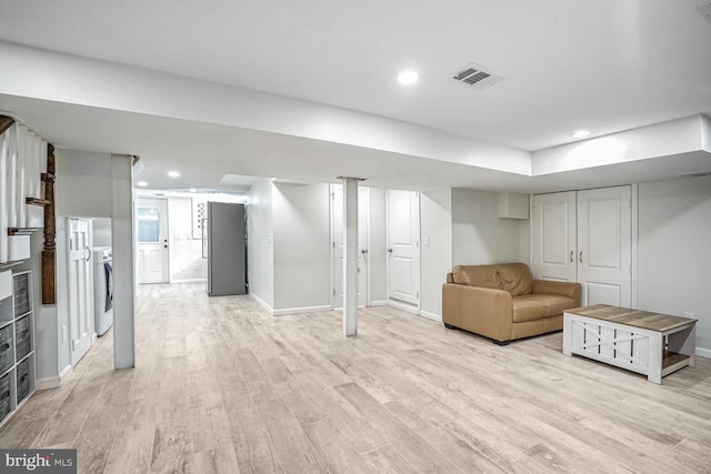 basement featuring washer / dryer and light hardwood / wood-style flooring