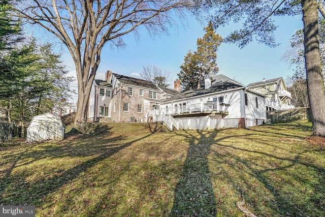 rear view of property featuring a storage shed, a deck, and a lawn