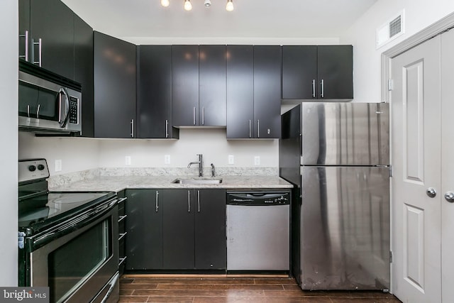 kitchen with stainless steel appliances, light stone counters, and sink