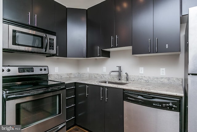 kitchen with light stone counters, sink, and stainless steel appliances