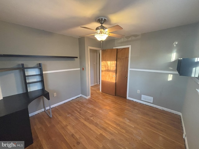 unfurnished bedroom featuring hardwood / wood-style floors, ceiling fan, and a closet