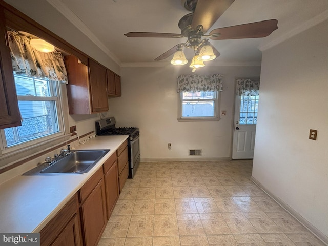 kitchen with sink, ornamental molding, stainless steel range with gas stovetop, and ceiling fan