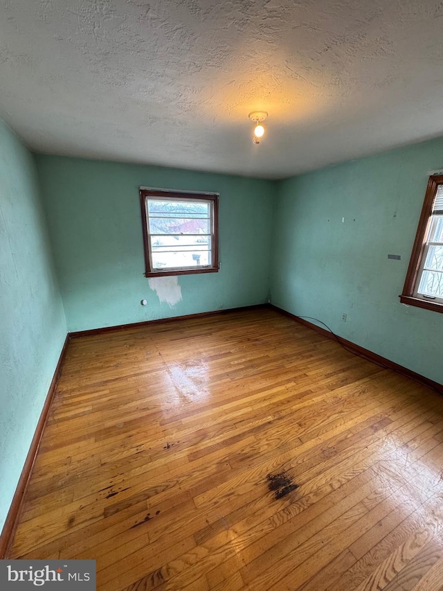 empty room with a textured ceiling and light hardwood / wood-style flooring