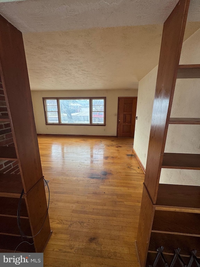 unfurnished living room featuring a textured ceiling and light hardwood / wood-style flooring