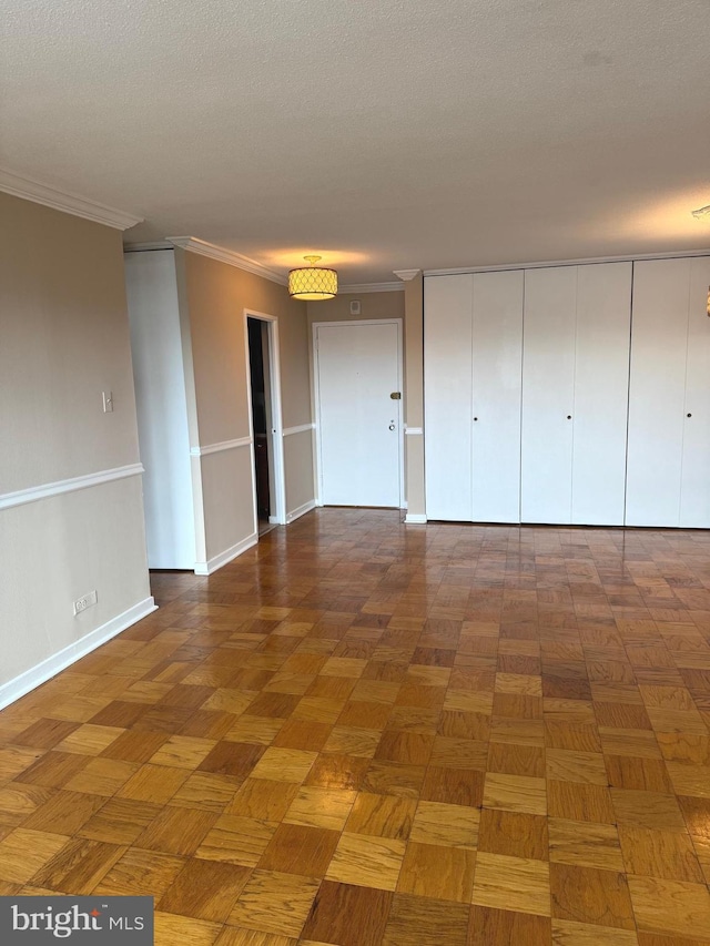 interior space with dark parquet flooring, ornamental molding, and a textured ceiling