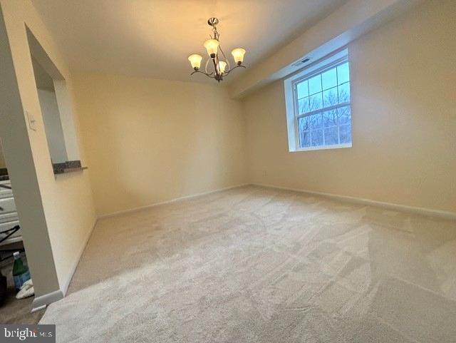 unfurnished room featuring an inviting chandelier and carpet floors