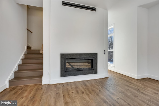 3234 Royal Fern Pl, Rockville, MD 20852 - unfurnished living room with stairs, wood finished floors, a glass covered fireplace, baseboards, and visible vents
