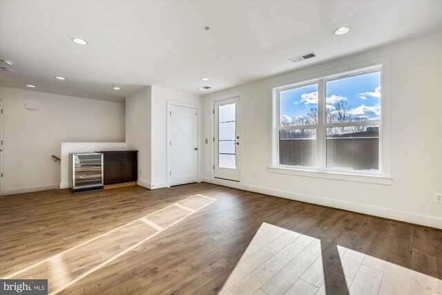 3234 Royal Fern Pl, Rockville, MD 20852 - unfurnished living room with a healthy amount of sunlight, visible vents, wine cooler, and hardwood / wood-style floors