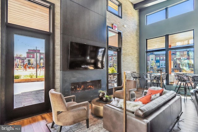 3234 Royal Fern Pl, Rockville, MD 20852 - living room featuring brick wall, wood finished floors, a towering ceiling, and a large fireplace