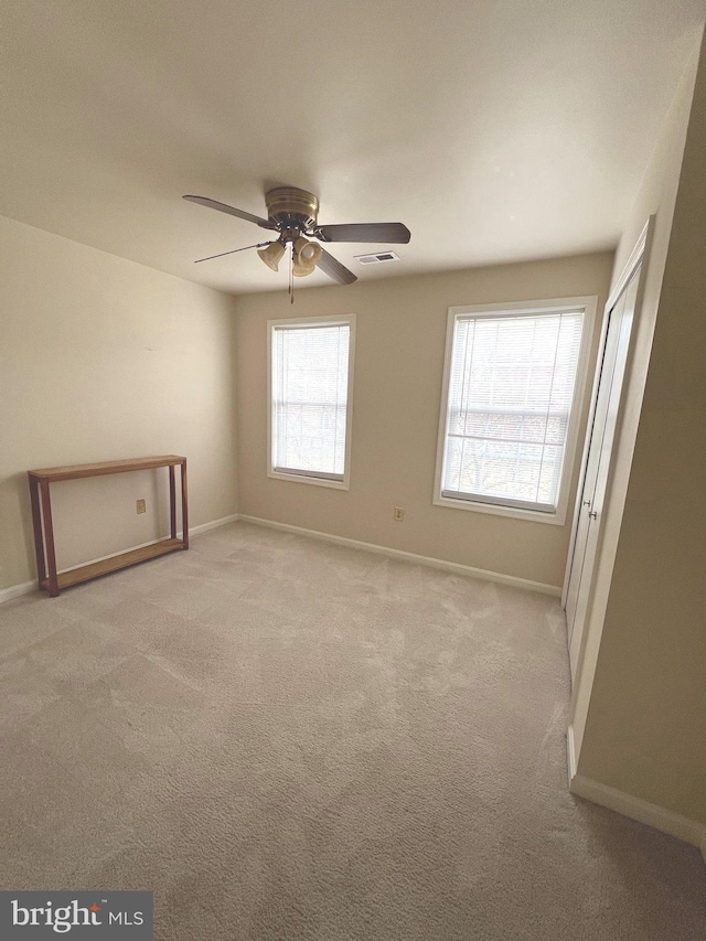 empty room featuring ceiling fan and light colored carpet