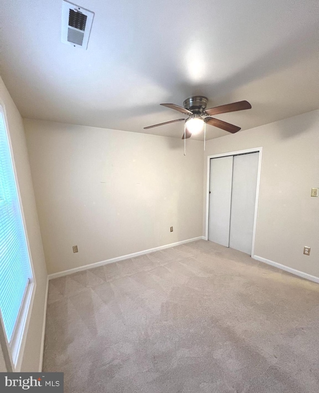 unfurnished bedroom with light carpet, ceiling fan, and a closet