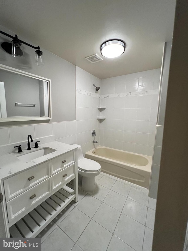 full bathroom with tile patterned floors, tiled shower / bath combo, tile walls, and toilet