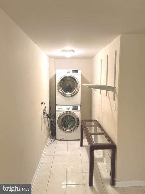 laundry room featuring stacked washer / drying machine and light tile patterned flooring