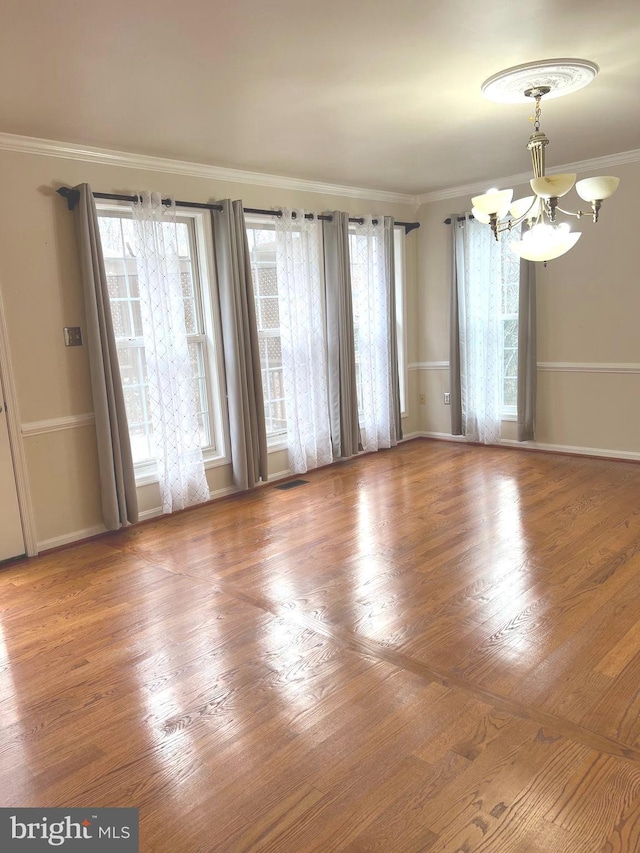 spare room featuring ornamental molding, hardwood / wood-style floors, and a notable chandelier