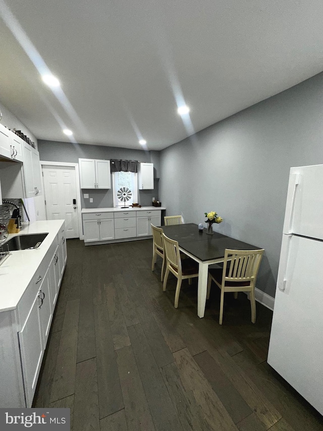 kitchen with dark wood-type flooring, sink, white refrigerator, and white cabinetry