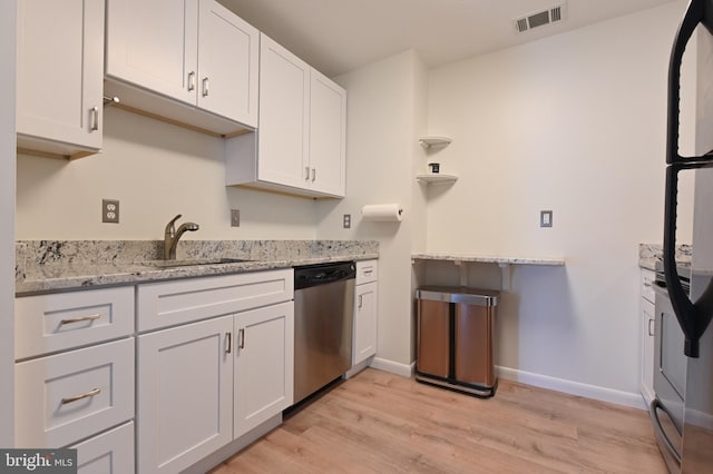 kitchen with visible vents, dishwasher, freestanding refrigerator, white cabinetry, and a sink