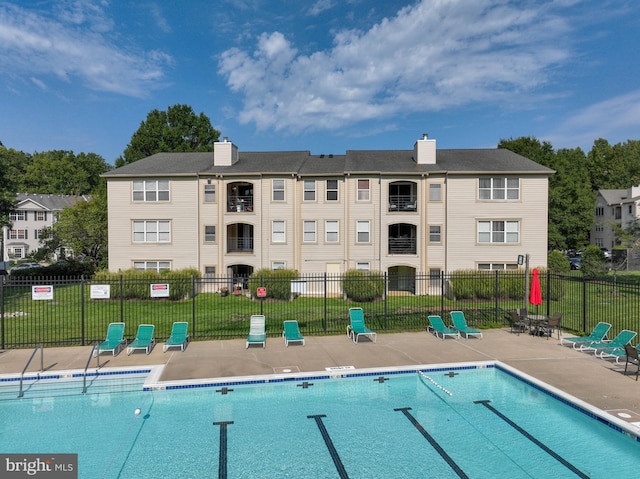 community pool featuring a yard, a patio, and fence