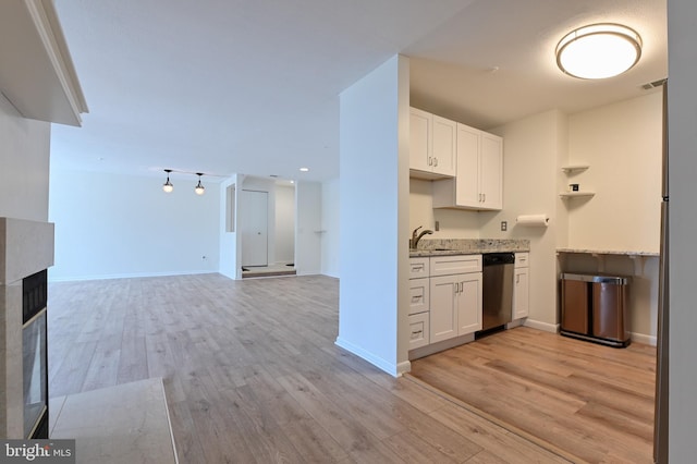 kitchen featuring light stone countertops, a sink, white cabinets, dishwasher, and light wood-type flooring