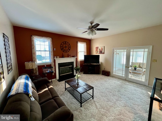 living area featuring a fireplace with flush hearth, plenty of natural light, carpet flooring, and a ceiling fan