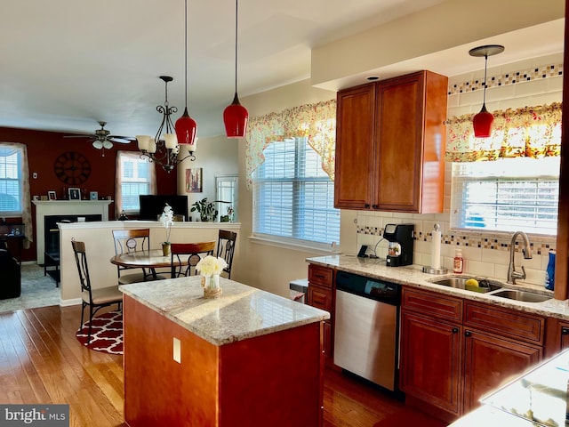 kitchen with sink, hanging light fixtures, stainless steel dishwasher, and a kitchen island