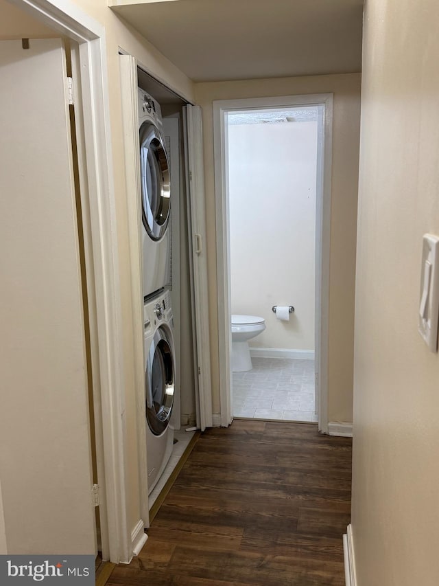 laundry room featuring dark hardwood / wood-style floors and stacked washer and clothes dryer