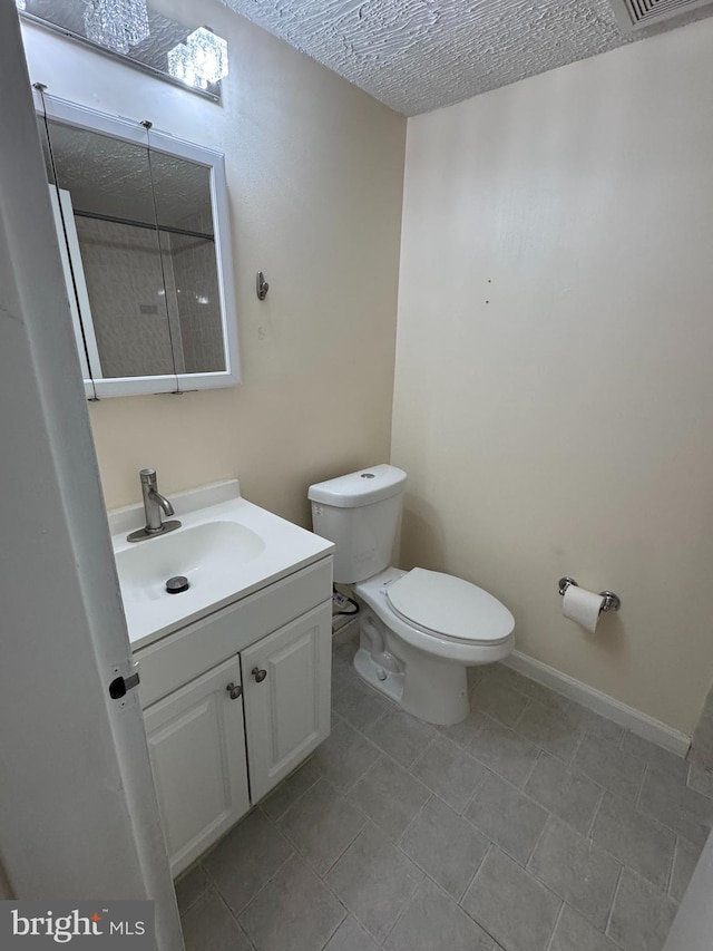 bathroom featuring a textured ceiling, toilet, and vanity