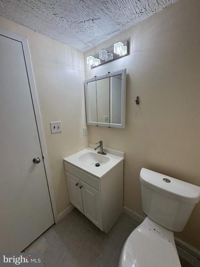 bathroom featuring a textured ceiling, toilet, vanity, and tile patterned flooring