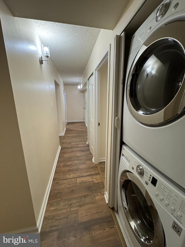 laundry room featuring stacked washer / dryer, a textured ceiling, and dark hardwood / wood-style floors