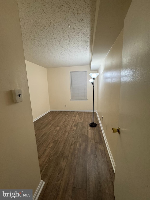 spare room featuring a textured ceiling and dark hardwood / wood-style floors