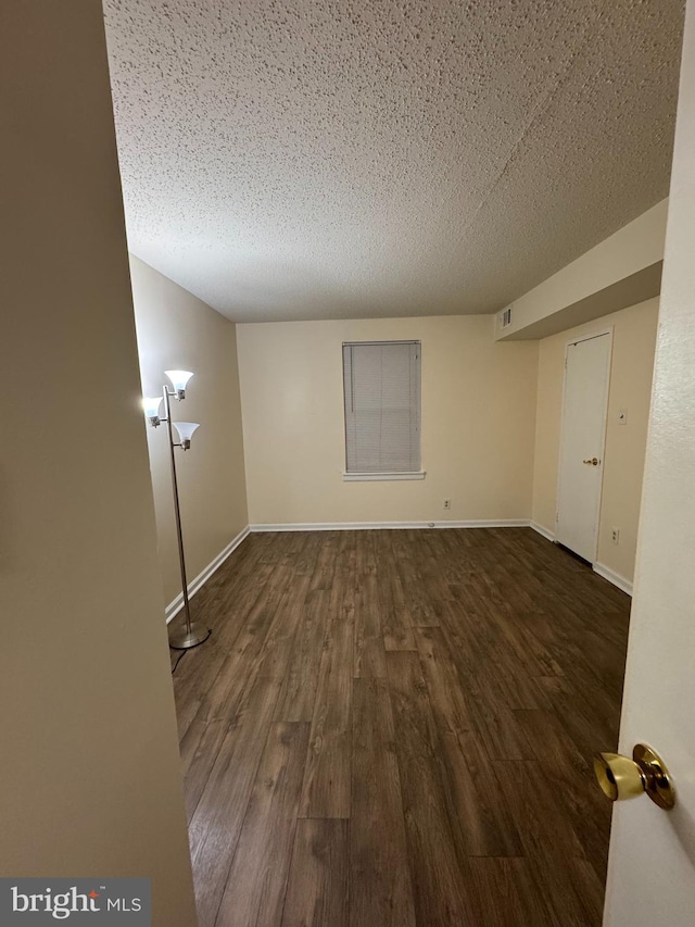 spare room with dark wood-type flooring and a textured ceiling