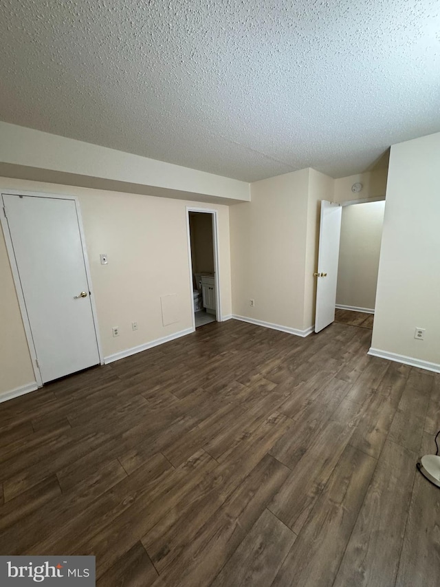 empty room with dark wood-type flooring and a textured ceiling