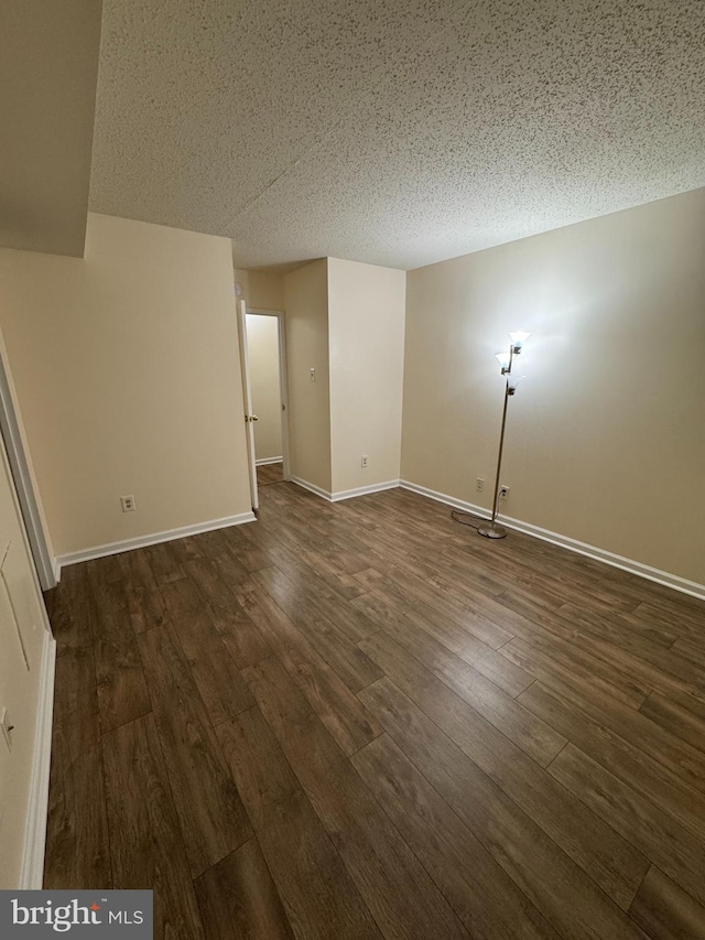 empty room featuring a textured ceiling and dark hardwood / wood-style floors