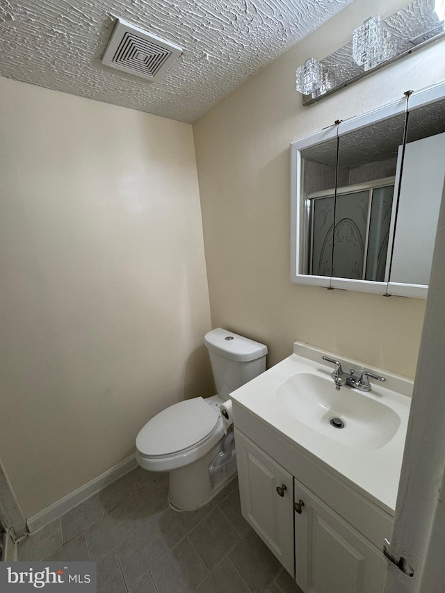 bathroom featuring vanity, toilet, a textured ceiling, and a shower with door